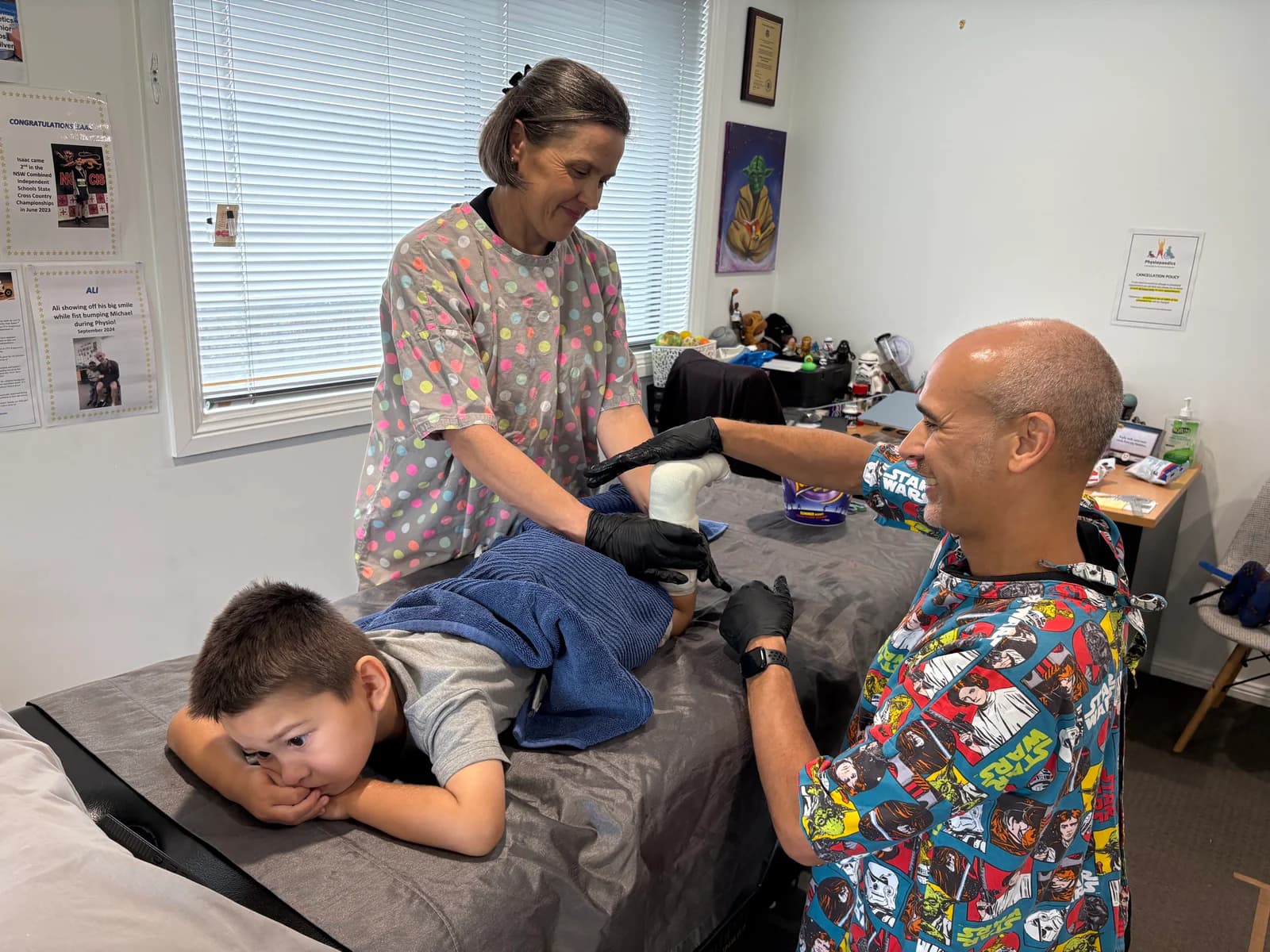 Two physios applying serial casts while a boy relaxes on the plinth